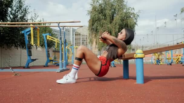 Sportif güzel bir kadın spor sahasında spor salonunda spor lastiğiyle kalça köprüsü yapıyor. — Stok video