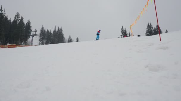 Snowboardista sjíždí z kopce ve zpomaleném filmu v lyžařském středisku, aktivní odpočinek v zimních horách. — Stock video