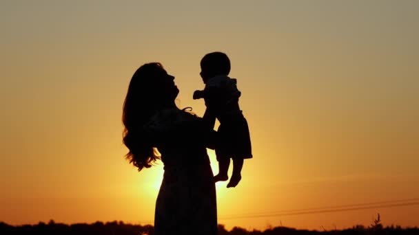 Onherkenbaar silhouet bij zonsondergang, gelukkig moeder kotst haar baby — Stockvideo