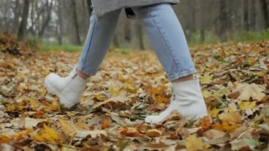 Sarı yapraklarla ormanda yürüyen tanınmayan bir kadının yakın çekim görüntüsü.