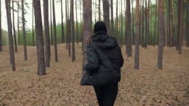 Korkmuş genç kız ormanda kovalamacadan kaçıyor, ağaçların arasında koşuyor.