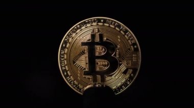 Bitcoin para siyah arkaplanda ışık ile aydınlatılmış.