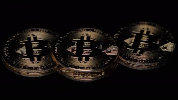 Siyah arkaplanda ışıkla aydınlatılmış üç bitcoin para — Stok video
