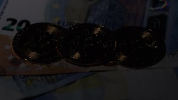 Tiga bitcoin koin terletak pada uang mata uang euro, diterangi dengan cahaya — Stok Video