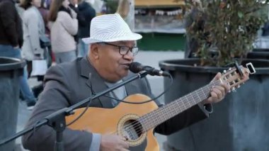 Barselona, İspanya - Kasım 2021: Sokak müzisyeni Plaza Catalunya 'da gitar çalıp şarkı söylüyor, turistler arka planda.