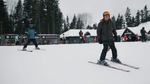 ブコヴェル、ウクライナ、 2021年12月:スキーリゾートで下り坂に行くスキーヤー、冬の山の中で活発な休息 — ストック動画