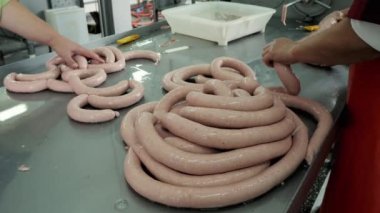 Bir et fabrikasında endüstriyel sosis üretimi, işçiler sosisi şekillendiriyor..