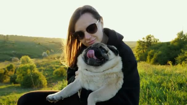 La mujer abraza y besa a su perro. Gracioso pug cansado relajarse en manos del propietario, el amor a los animales. — Vídeos de Stock