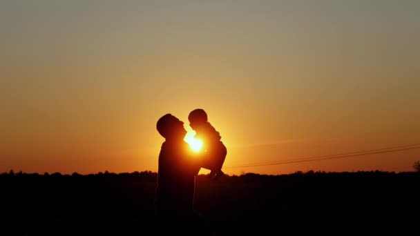 Happy father throws up his baby, Unrecognizable silhouette at sunset. — Stock videók