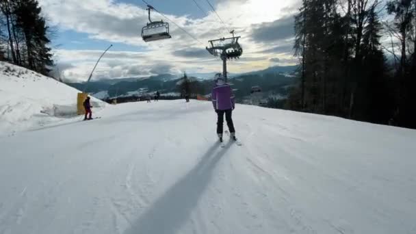 Skiers going downhill in a ski resort, active rest in winter mountains — Stockvideo