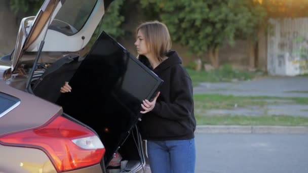 Kobieta śmieszne próbuje umieścić zakupiony nowoczesny telewizor w bagażniku samochodu na parkingu supermarket — Wideo stockowe