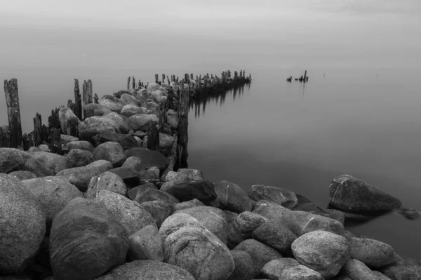 石と木の脚でできた古い桟橋は金属製のネジで残され水面は穏やかです — ストック写真