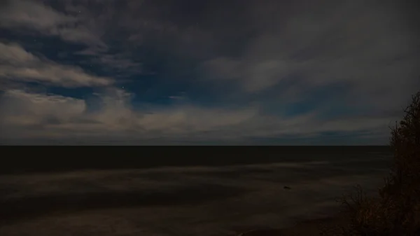 雲の後ろの星や北の光の反射を求めて海のそばの穏やかな水面 — ストック写真