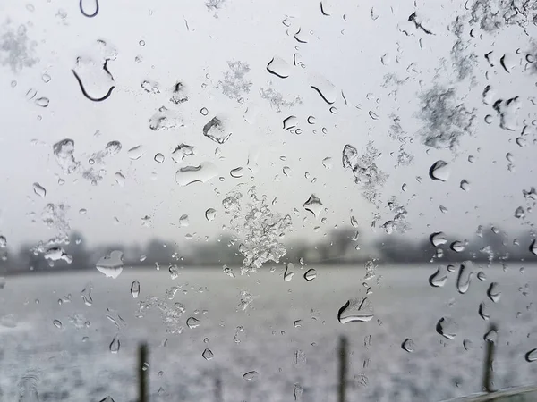 雪がぼやけた窓の上で雨と雪に覆われた風景の後ろ ストック画像