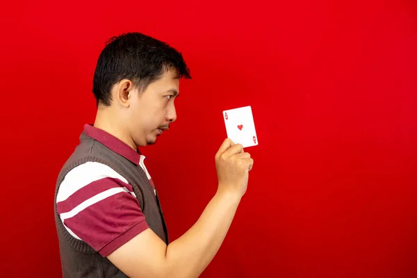 Poker kartı ya da as tutan yakışıklı bir Asyalı. kırmızı arkaplan.
