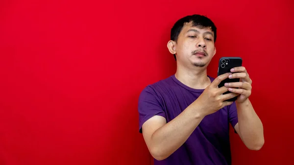 Ein Asiatischer Mann Lila Shirt Blickt Auf Sein Smartphone Roter — Stockfoto