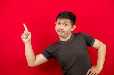 Siyah tişört giyen yakışıklı Asyalı bir adamın yan görünüş portresi. Kırmızı arka plandaki boşluğu gösteren bir gülümseme..