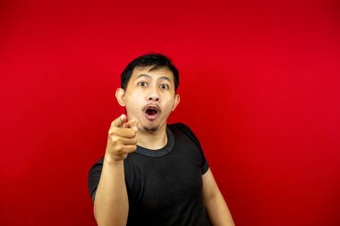 Siyah tişörtlü Asyalı suratlı adam elini gösteriyor. kırmızı arkaplan.