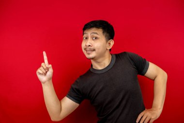 Siyah tişört giyen yakışıklı Asyalı bir adamın yan görünüş portresi. Kırmızı arka plandaki boşluğu gösteren bir gülümseme..