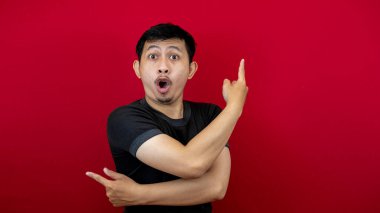 Siyah tişört giyen yakışıklı Asyalı bir adamın yan görünüş portresi. Kırmızı arka plandaki boşluğu gösteren bir gülümseme..
