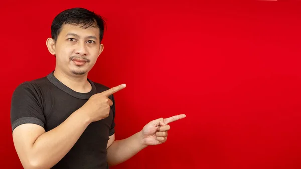 Siyah tişört giyen yakışıklı Asyalı bir adamın yan görünüş portresi. Kırmızı arka plandaki boşluğu gösteren bir gülümseme..