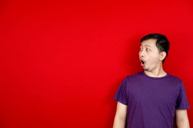 Asyalı adam şaşırmış bir yüzle içerik için boş bir yer gösterdi. Reklam modeli konsepti. kırmızı arkaplan. 