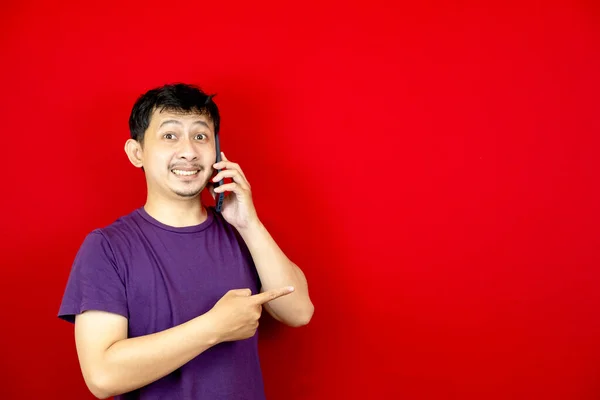 Азиатский Мужчина Улыбается Время Разговора Телефону Указывает Направление Пустое Место — стоковое фото