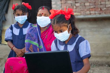 Annesi ve kız kardeşi loptop 'u işaret ederken Hindistan köyü devlet okulu öğrencilerinin dizüstü bilgisayar sistemi