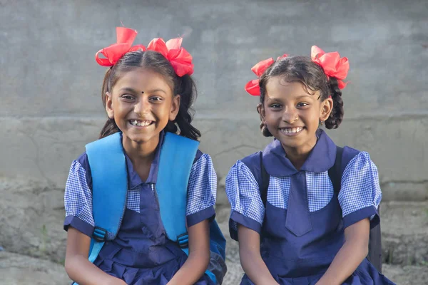 Köylü kadın okulunun saçını örüyor. Kızları evlerinde bir karyolada oturuyor.