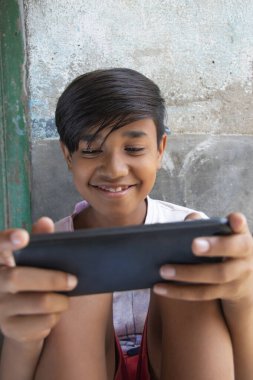 Gülümseyen çocuk akıllı telefonda tek başına oynuyor.