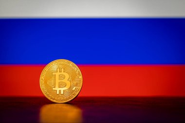 Arka planda Rusya bayrağı olan altın maddi Bitcoin