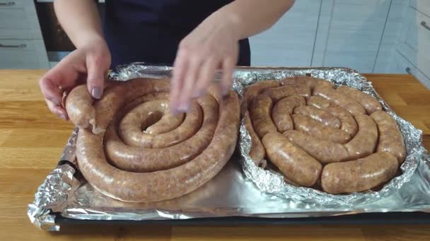 Le cuisinier met la saucisse crue sur une plaque à pâtisserie. le processus de fabrication de saucisses grillées maison à partir de viande hachée. — Video