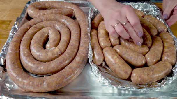 El cocinero pone la salchicha cruda en una bandeja para hornear. el proceso de elaboración de embutidos a la parrilla caseros a partir de carne picada. — Vídeo de stock