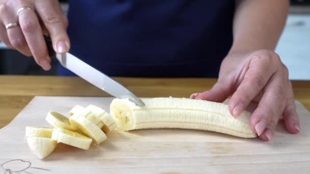 Mujer de corte de plátano en la tabla de cortar de cerca 4K — Vídeo de stock