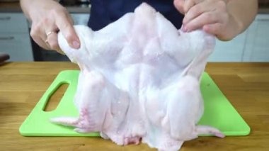 Kız şef çiğ tavuk etini tahtada keser. Izgara tavuk pişirme işlemi