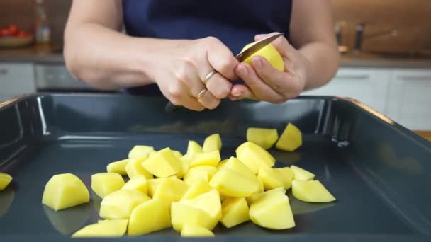 A szakács a burgonyát sütőlapra vágja. zöldségpörkölés folyamata a sütőben. — Stock videók