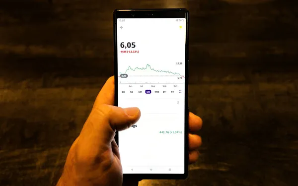 Mobil uygulamalı akıllı telefonu tutan bir erkek. Borsa ticaret grafiğini analiz eden tüccar.