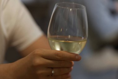 Kadın bardakla bardağı tutuyor ve doğal arka planda bulanıklık var.