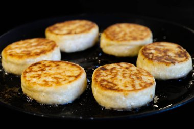 Süzme peynirli kekler kızartma tavasında kızartılır. Lezzetli ev yapımı yemekler pişirme süreci. Peynirli krep ya da şurup..