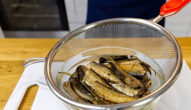 Sprats fish on kitchen board in colander.