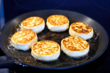 Süzme peynirli kekler kızartma tavasında kızartılır. Lezzetli ev yapımı yemekler pişirme süreci. Peynirli krep ya da şurup..