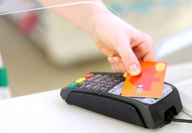 Müşteri kartlarını NFC teknolojisi konseptiyle ödüyor. Kablosuz terminal posizyon makinesindeki eczanede işlem.