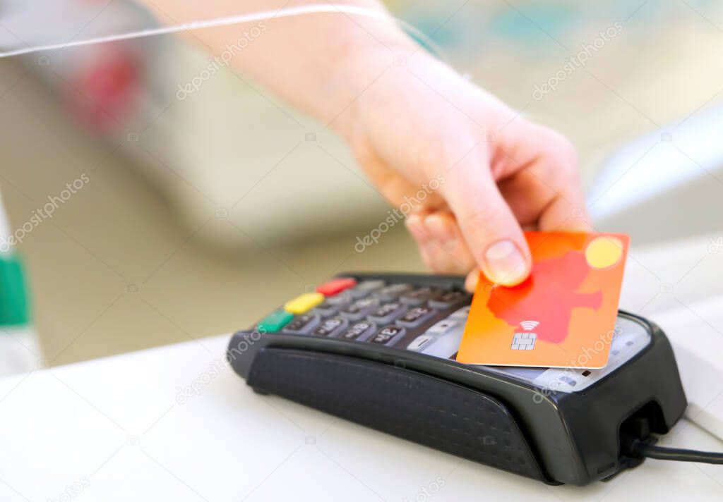 customer pay hold credit card with contactless nfc technology concept. transaction in pharmacy store on wireless terminal pos reader machine.