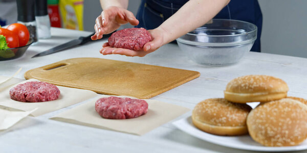 Womans hand forming a beef meat for a hamburger party. Portioning ground meat. Homemade burgers. Making food at home.