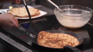 Kadın tavadaki gözlemeyi çeviriyor. Krepler tavada kızarır. Ev yapımı Rus blini pişirme işlemi. Krepten duman çıkıyor. Yavaş çekim videosu