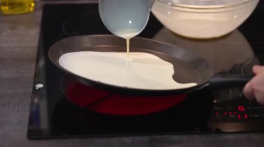 Yavaş çekimde krep hamurunu tavaya döken kadın. Krepler tavada kızarır. Ev yapımı Rus blini pişirme işlemi. Krepten duman çıkıyor. yavaş çekim