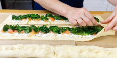 Aşçı hamura ıspanak ve alabalık koyar. Çelenk pişirme işlemi şeklinde lezzetli bir Noel turtası. Kapat.