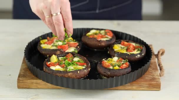 Γεμιστά μανιτάρια Portobello διαδικασία μαγειρέματος. γυναίκα βάζει πράσινο κρεμμύδι πάνω από τα μαγειρεμένα champignons γεμιστά με ντομάτες και μοτσαρέλα. — Αρχείο Βίντεο
