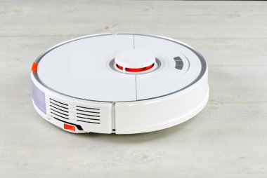 Robot süpürge ahşap zeminde odayı temizliyor. Akıllı temizlik ve çamaşır teknolojisi. Gelişmiş robot işi süpürmek ve sonra paspas.