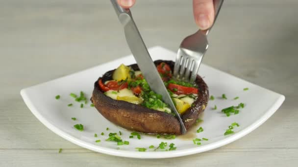 Stuffed Portobello mushrooms. woman cuts with a knife and tastes champignons stuffed with tomatoes and mozzarella. — Stock Video